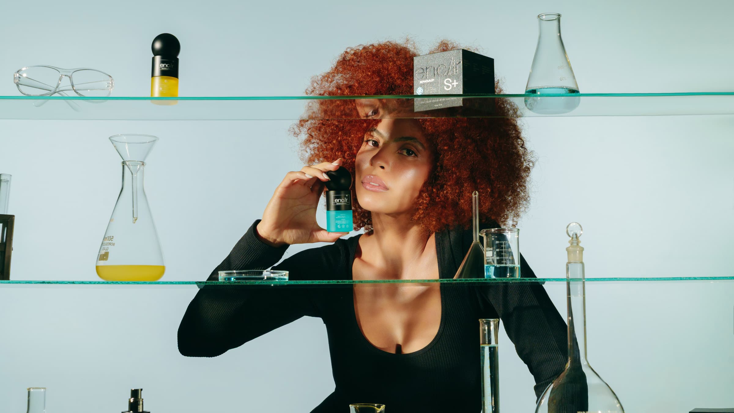 Model holding the Enclir S+ serum behind glass lab shelves with the C+ serum and ENCAP S+ box